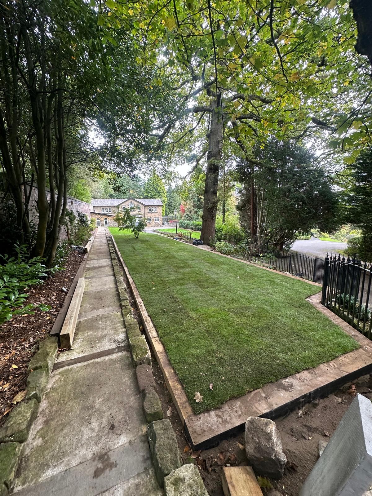 A garden lawn beside mature trees and a long gravel path